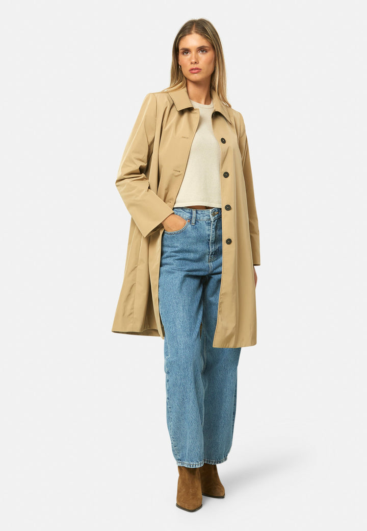woman wearing beige mac trench coat over jeans