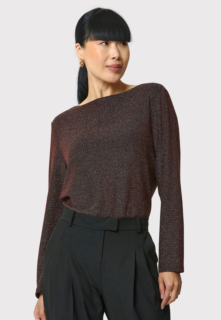 Introducing the Roxanne Copper Shimmer Top, an updated version of the beloved best-selling faux-wrap top. This season's design features a beautifully draped neckline for an elegant touch. With its hip-length cut and full-length sleeves, this top combines comfort and chic style effortlessly. Crafted from a black sparkly jersey fabric, it adds a touch of glamour to any outfit. Embrace the ultimate in comfortable chic with the Roxanne Copper Shimmer Top.