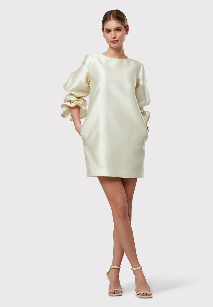 Step into the spotlight as the ideal guest with Aurora, a chic short shift dress that boasts a statement puff-ball sleeve. Falling gracefully above the knee, it's crafted from iridescent Ivory fabric, offering a distinctive look. The dress comes with convenient side seam pockets and an eye-catching sleeve detail. Make a grand entrance in Aurora.