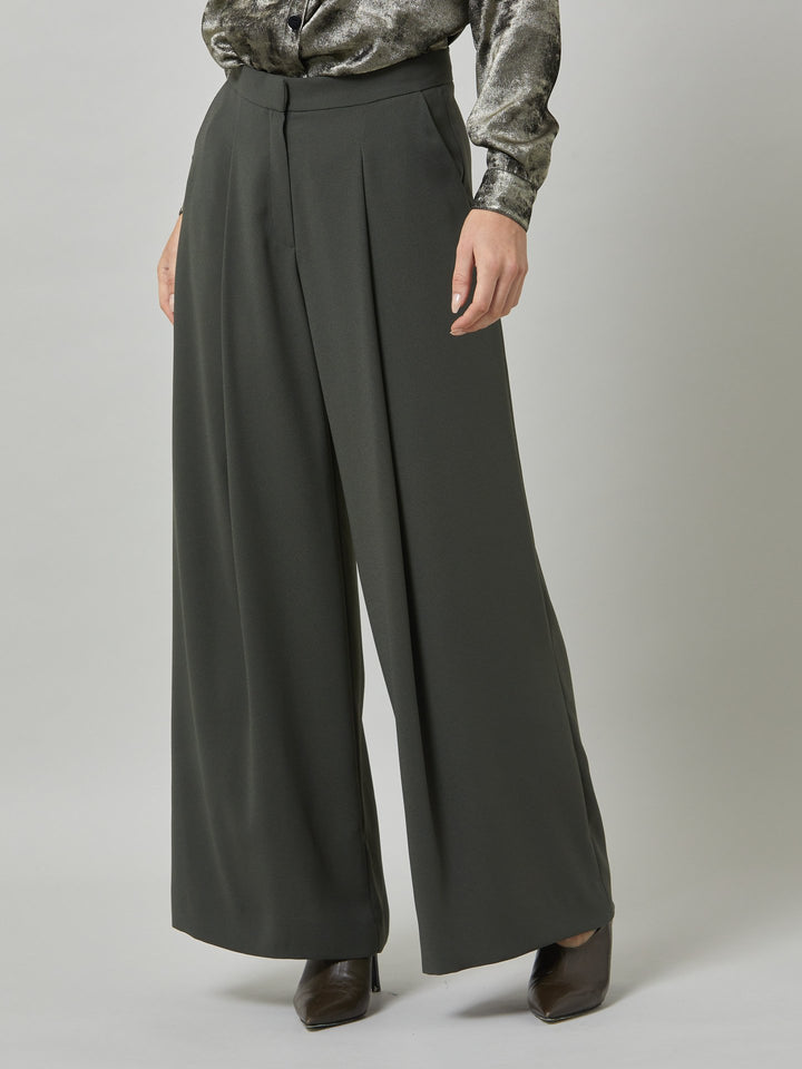 Charlize, a wide-leg palazzo pant. crafted in a satin back crepe in rich olive features deep pleats, sharp front crease & side pockets. A high-waisted trouser made to take you from desk to dinner with a relaxed & refined silhouette. Style with flats or dress up with heels.