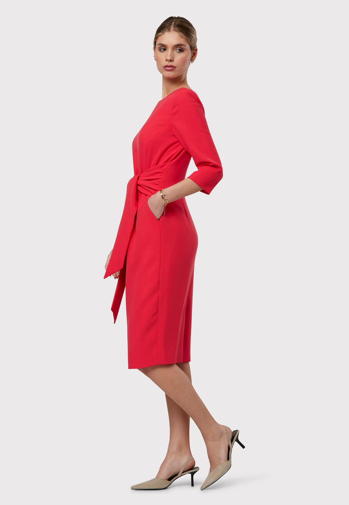 Transition seamlessly from desk to dinner in the Karen Begonia Orange Dress. This figure-flattering silhouette boasts an attached belt that gathers at the side seams to accentuate the waist. Its pencil skirt falls to a chic mid-calf length, enhanced by a refined slash neck for added sophistication. Complete with practical pockets and crafted from sustainably sourced fibers with a touch of stretch, this dress ensures both style and comfort.