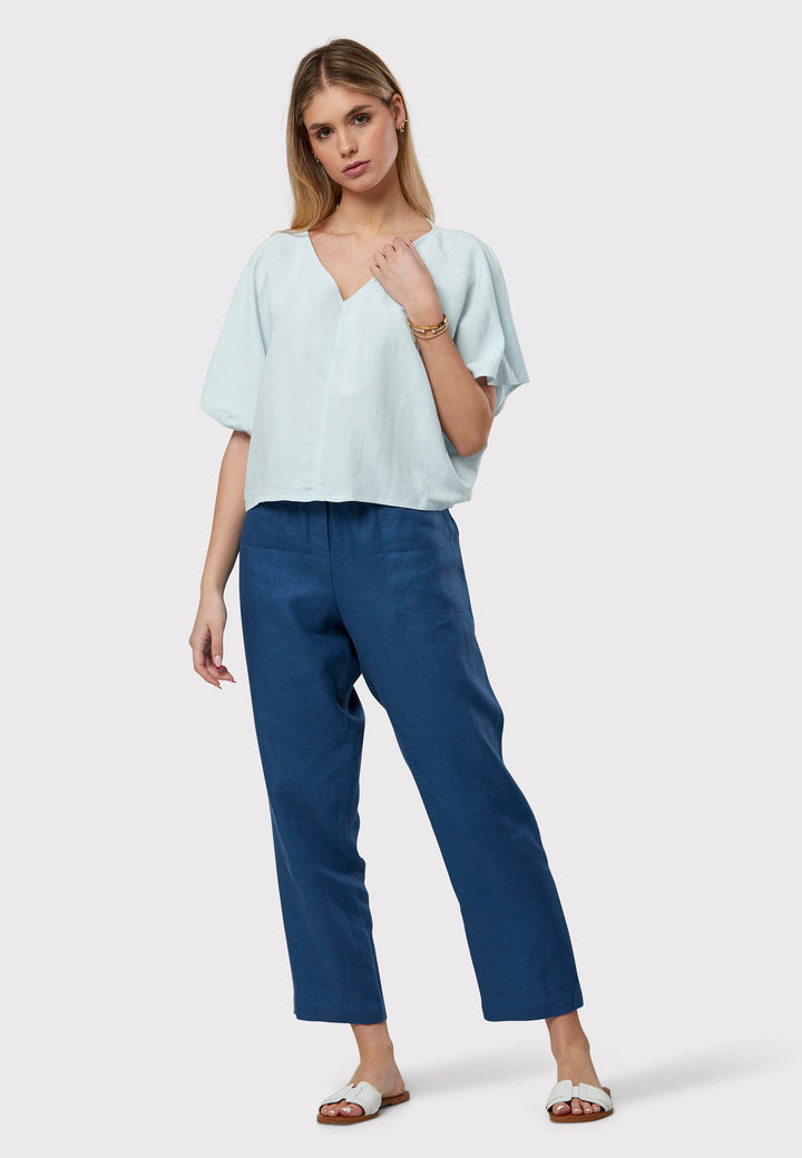 The Quinn Blue Linen Shirt embodies a relaxed warm-weather feel, crafted from breathable pure linen with a flattering v-neck design. Its easy fit ensures summer comfort, complemented by subtle pleat detailing on the back hem for a stylish touch.
