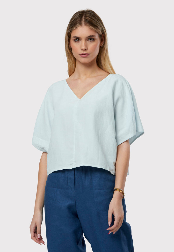 The Quinn Blue Linen Shirt embodies a relaxed warm-weather feel, crafted from breathable pure linen with a flattering v-neck design. Its easy fit ensures summer comfort, complemented by subtle pleat detailing on the back hem for a stylish touch.