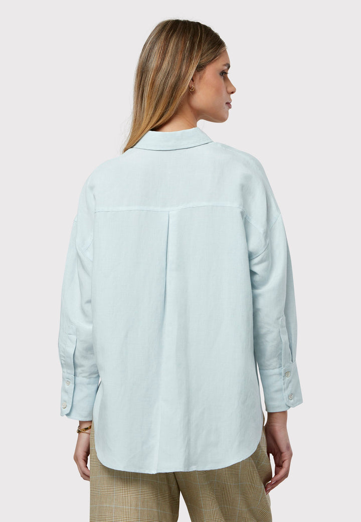 Embrace effortless style with this sustainable linen boyfriend shirt in a versatile blue hue. Its oversized, minimalist design includes long sleeves and a classic collar, offering timeless appeal. The button-through front and rounded hem meld comfort with style, establishing it as a versatile wardrobe essential.