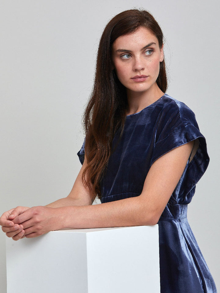 Occasionwear modernized. Meet the Shiv Juniper blue dress in Luxurious fluid velvet. An easy-fitting silhouette with side seam pockets falls to the mid-calf & features a side slit, dropped sleeves, and an elegant key-hole back neck detail. Attending a winter wedding? This is the dress for you.