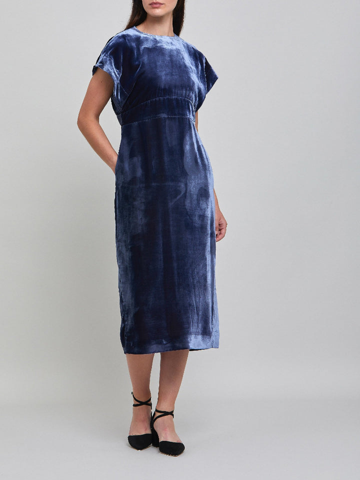 Occasionwear modernized. Meet the Shiv Juniper blue dress in Luxurious fluid velvet. An easy-fitting silhouette with side seam pockets falls to the mid-calf & features a side slit, dropped sleeves, and an elegant key-hole back neck detail. Attending a winter wedding? This is the dress for you.