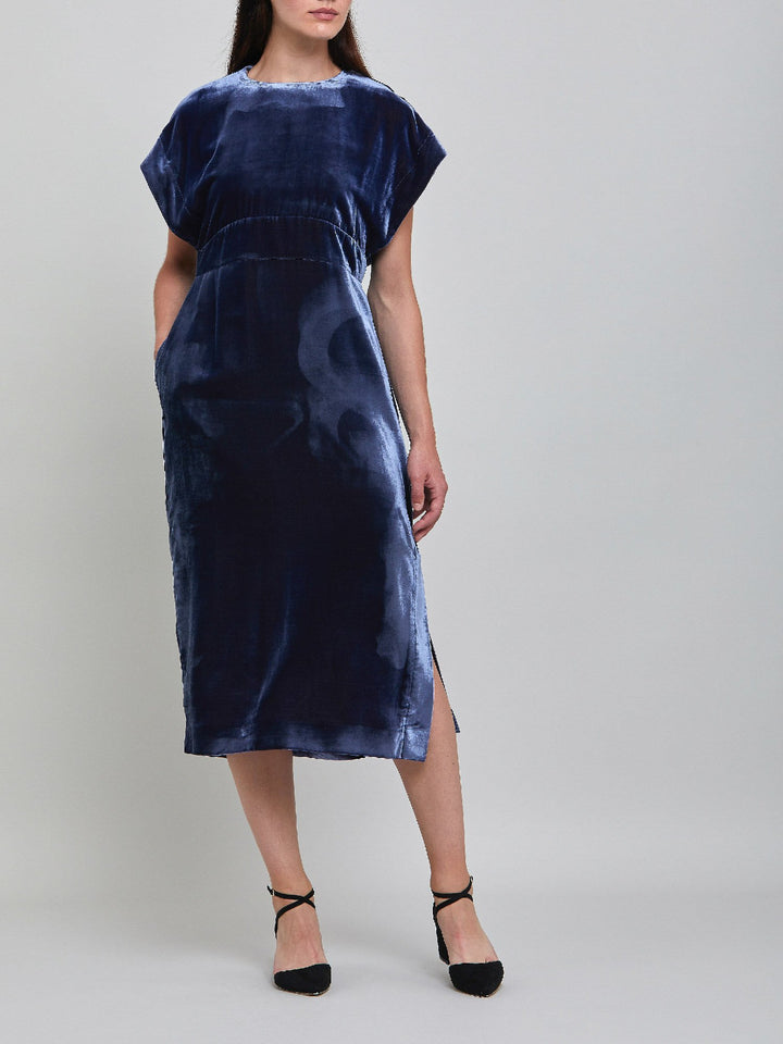 Occasionwear modernized. Meet the Shiv Juniper blue dress in Luxurious fluid velvet. An easy-fitting silhouette with side seam pockets falls to the mid-calf & features a side slit, dropped sleeves, and an elegant key-hole back neck detail. Attending a winter wedding? This is the dress for you.