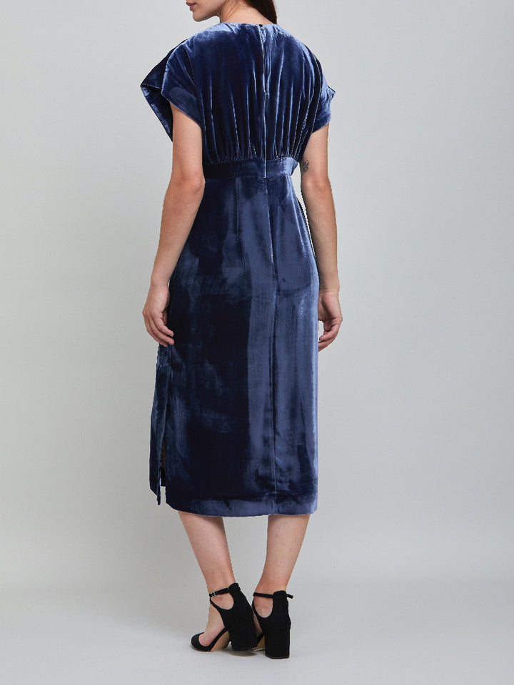 Occasionwear modernized. Meet the Shiv Juniper blue dress in Luxurious fluid velvet. An easy-fitting silhouette with side seam pockets falls to the mid-calf & features a side slit, dropped sleeves, and an elegant key-hole back neck detail. Attending a winter wedding? This is the dress for you.