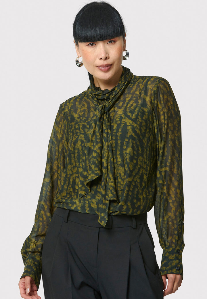 Anastasia Dark Green Forest Print Blouse, crafted from a luxurious viscose and silk blend, is perfect for your workwear wardrobe. This blouse features a round neckline, a chic pussy bow tie, and comes with a detachable slip. Pair it with the Marlena Sleeveless Chartreuse Green cashmere top, styled as a sweater vest, for a polished and professional look.