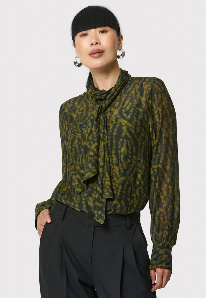 Anastasia Dark Green Forest Print Blouse, crafted from a luxurious viscose and silk blend, is perfect for your workwear wardrobe. This blouse features a round neckline, a chic pussy bow tie, and comes with a detachable slip. Pair it with the Marlena Sleeveless Chartreuse Green cashmere top, styled as a sweater vest, for a polished and professional look.