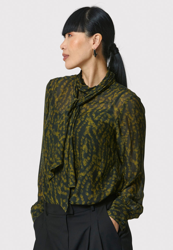 Anastasia Dark Green Forest Print Blouse, crafted from a luxurious viscose and silk blend, is perfect for your workwear wardrobe. This blouse features a round neckline, a chic pussy bow tie, and comes with a detachable slip. Pair it with the Marlena Sleeveless Chartreuse Green cashmere top, styled as a sweater vest, for a polished and professional look.
