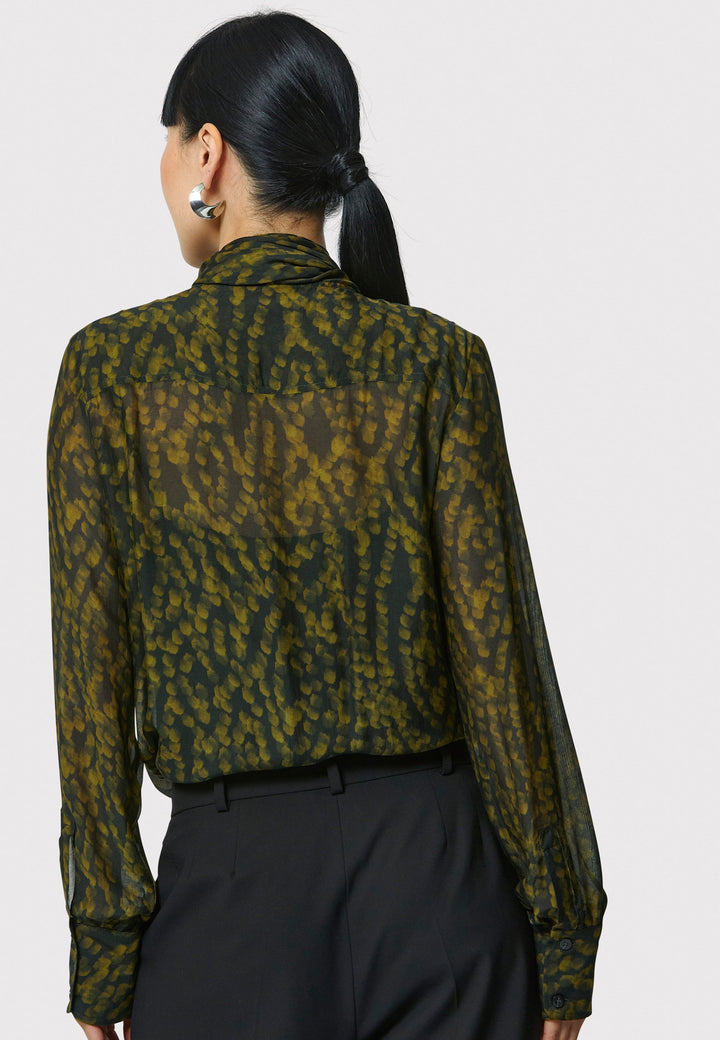 Anastasia Dark Green Forest Print Blouse, crafted from a luxurious viscose and silk blend, is perfect for your workwear wardrobe. This blouse features a round neckline, a chic pussy bow tie, and comes with a detachable slip. Pair it with the Marlena Sleeveless Chartreuse Green cashmere top, styled as a sweater vest, for a polished and professional look.