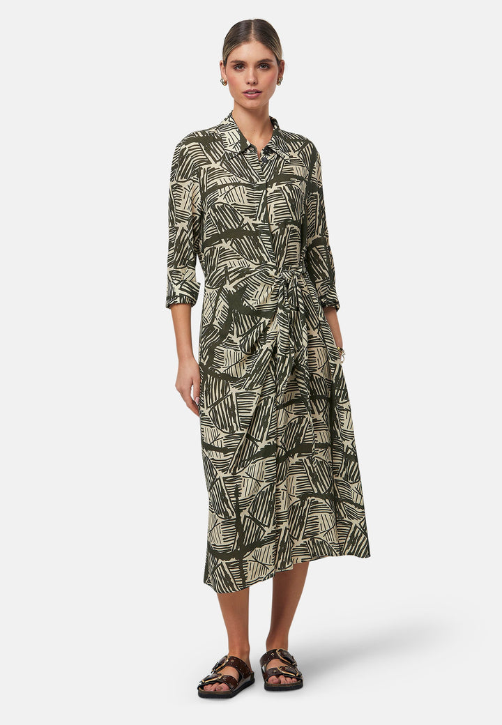 This Ashley Ogham Print Shirt Dress is a modern take on the classic shirt dress. Featuring a button-down front with a placket, full length sleeves with a button cuffed finish and simple shirt collar, it offers versatility and style. The wrap skirt ties off center to the front of the dress.