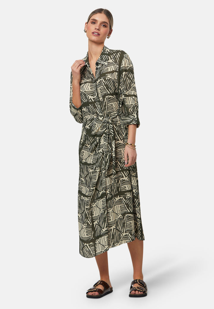 This Ashley Ogham Print Shirt Dress is a modern take on the classic shirt dress. Featuring a button-down front with a placket, full length sleeves with a button cuffed finish and simple shirt collar, it offers versatility and style. The wrap skirt ties off center to the front of the dress.