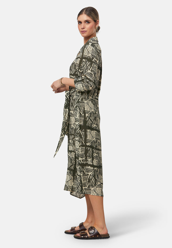 This Ashley Ogham Print Shirt Dress is a modern take on the classic shirt dress. Featuring a button-down front with a placket, full length sleeves with a button cuffed finish and simple shirt collar, it offers versatility and style. The wrap skirt ties off center to the front of the dress.