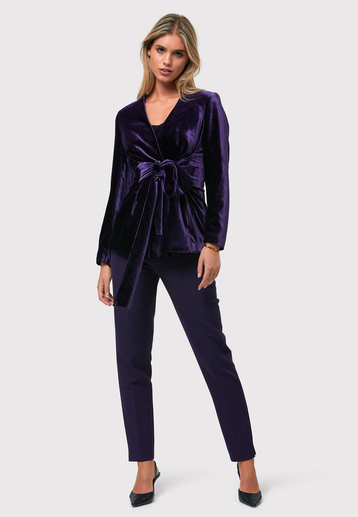 The Aurora Twilight Plum Velvet Jacket is an elegant addition to your evening wardrobe. Designed with a wrap front and a self-tie attached belt, allowing for a customizable fit. Pair with the matching Naomi trousers for a full glam look, or style it with the coordinating Jill trousers for a chic and simple style.