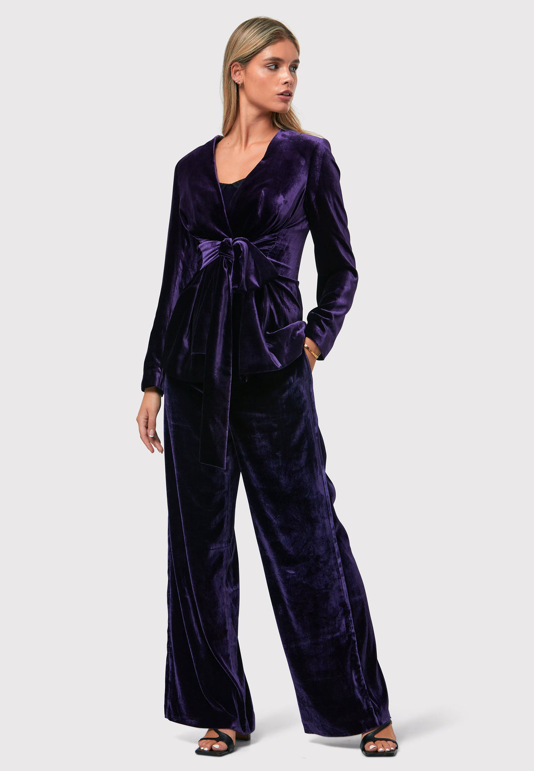 The Aurora Twilight Plum Velvet Jacket is an elegant addition to your evening wardrobe. Designed with a wrap front and a self-tie attached belt, allowing for a customizable fit. Pair with the matching Naomi trousers for a full glam look, or style it with the coordinating Jill trousers for a chic and simple style.