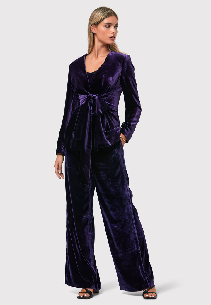 The Aurora Twilight Plum Velvet Jacket is an elegant addition to your evening wardrobe. Designed with a wrap front and a self-tie attached belt, allowing for a customizable fit. Pair with the matching Naomi trousers for a full glam look, or style it with the coordinating Jill trousers for a chic and simple style.