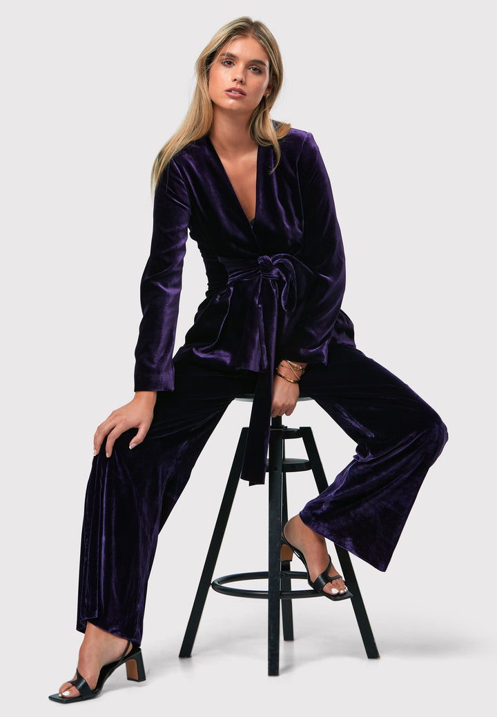 The Aurora Twilight Plum Velvet Jacket is an elegant addition to your evening wardrobe. Designed with a wrap front and a self-tie attached belt, allowing for a customizable fit. Pair with the matching Naomi trousers for a full glam look, or style it with the coordinating Jill trousers for a chic and simple style.
