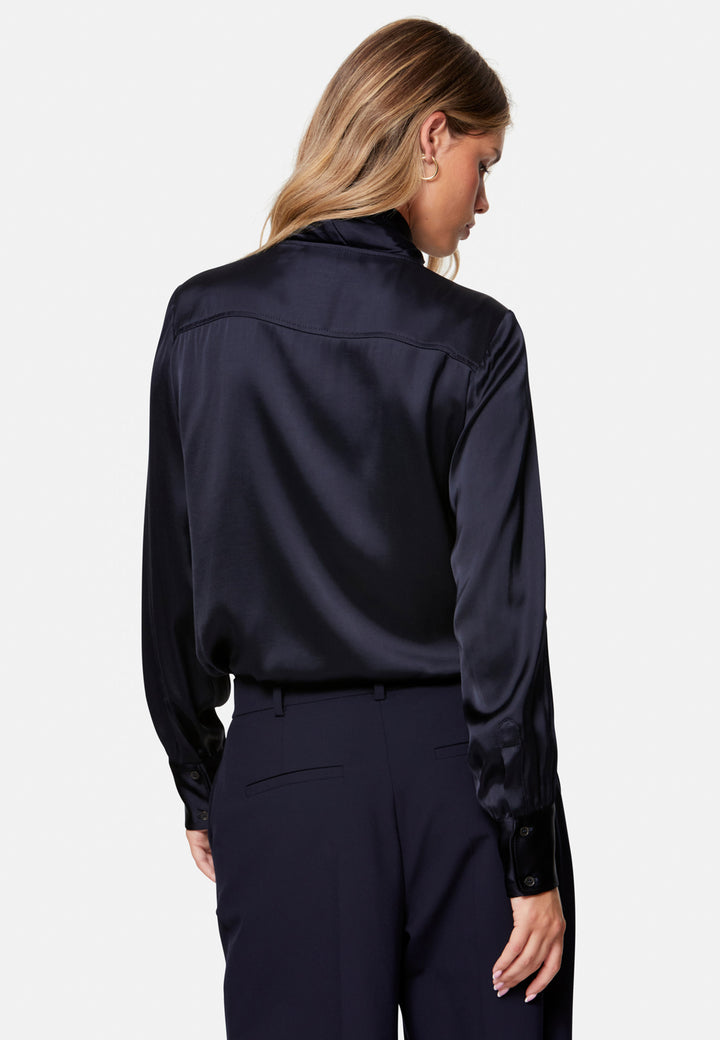 Woman wearing a navy satin shirt and pants on a white background