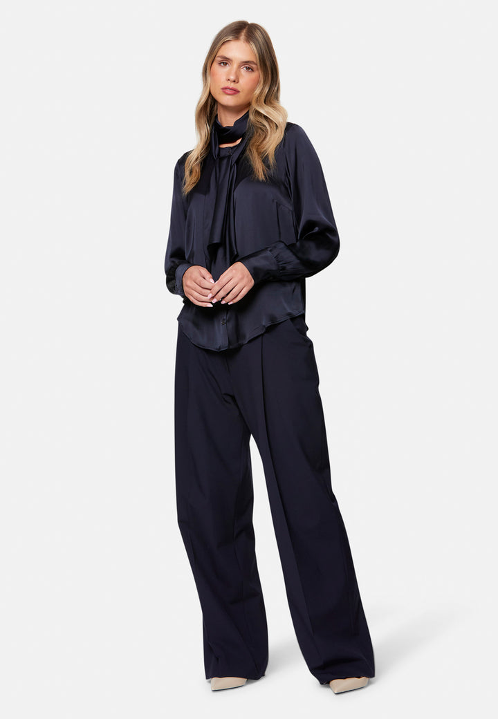 Woman wearing a navy outfit with a top and pants on a white background