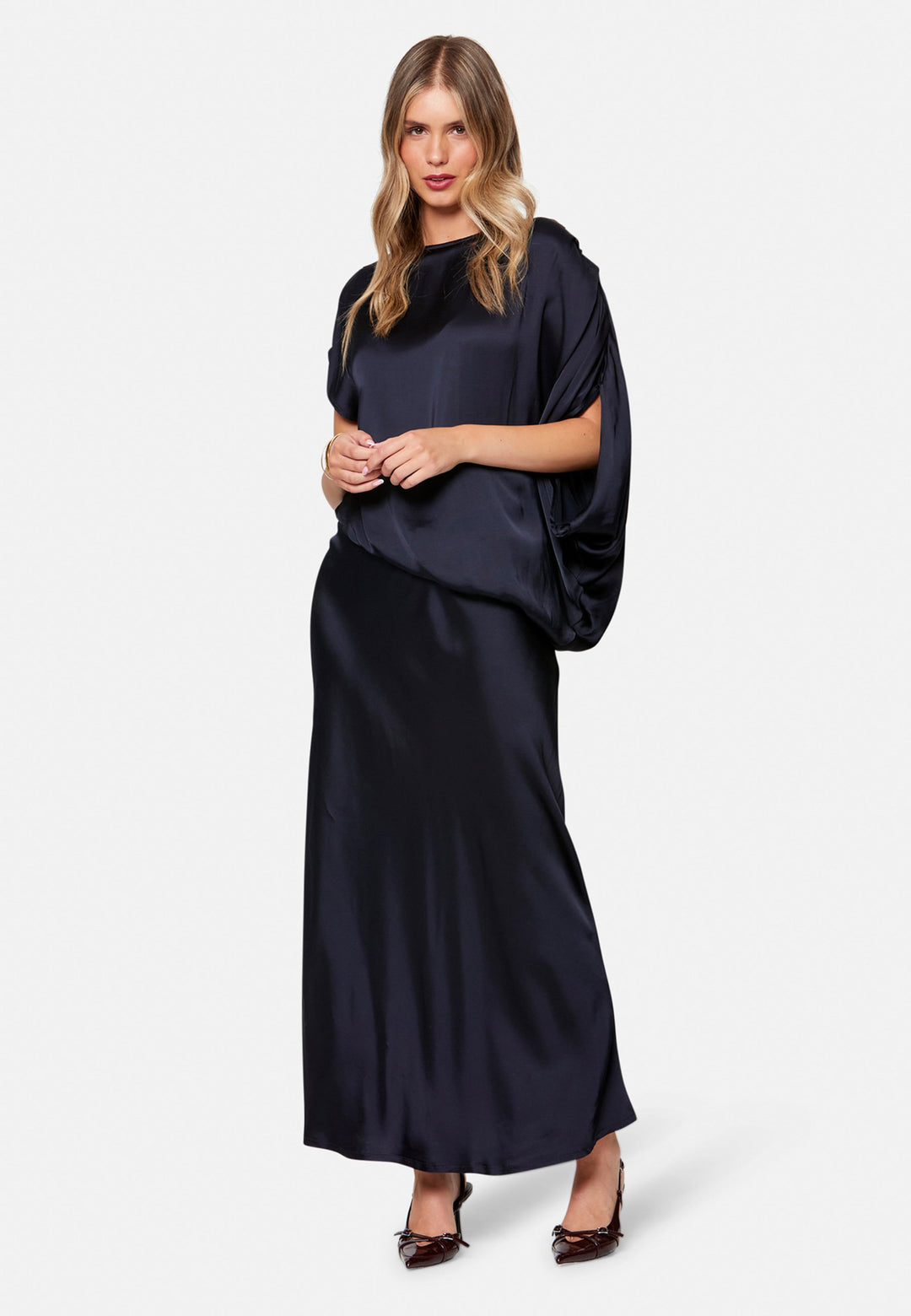 woman wearing navy satin assymetric blouse with matching midi skirt