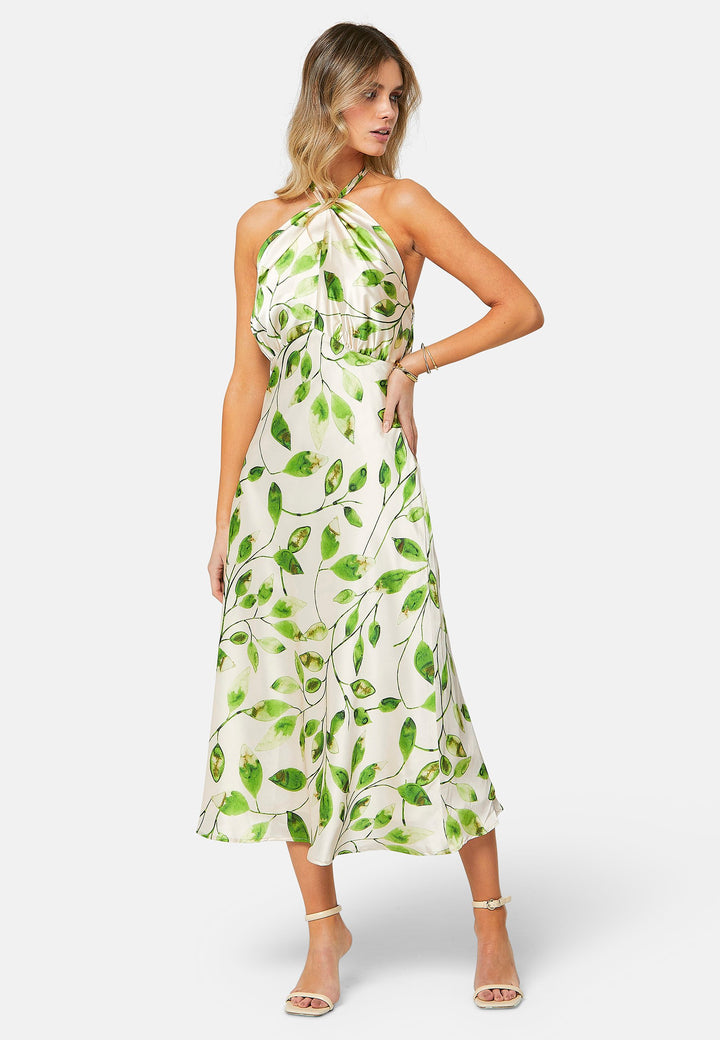 Introducing the Bronagh Leafy Print Dress: Elevate your summer wardrobe with this ankle-length halter neck dress, exquisitely designed for those special occasions. The dress features a bias-cut skirt that gracefully flows with every step, enhancing its feminine allure. The adjustable neck tie allows for a customizable fit, while the intricate knotted and twisted detail at the neckline adds an elegant touch to the halter design. 