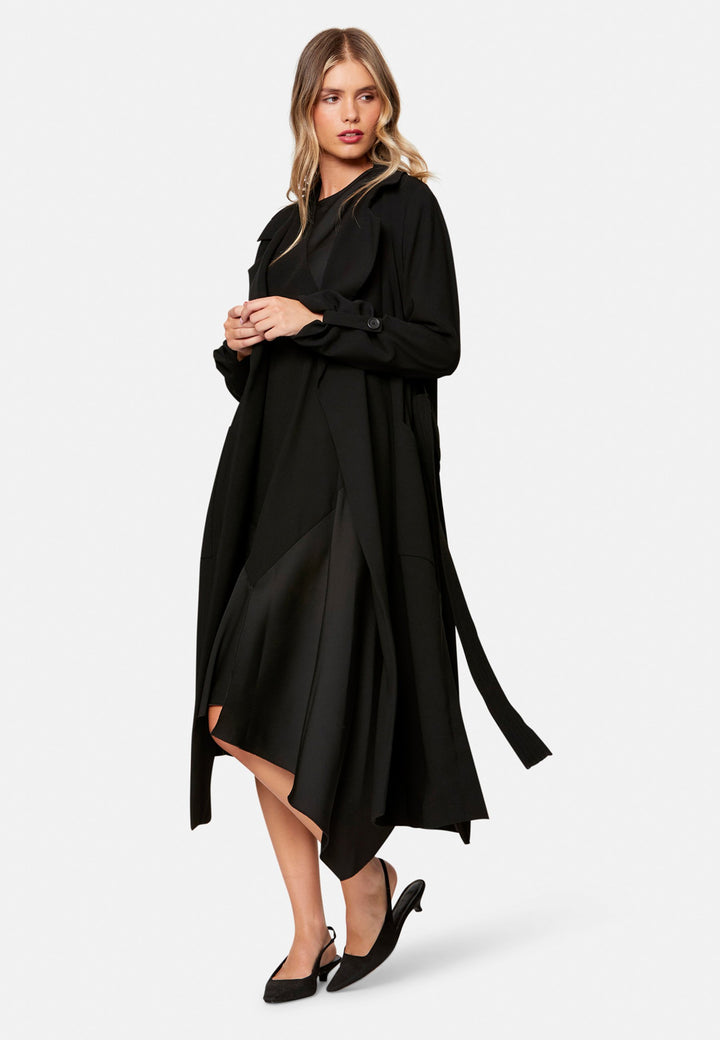 woman wearing black midi assymetric dress with black trenchcoat