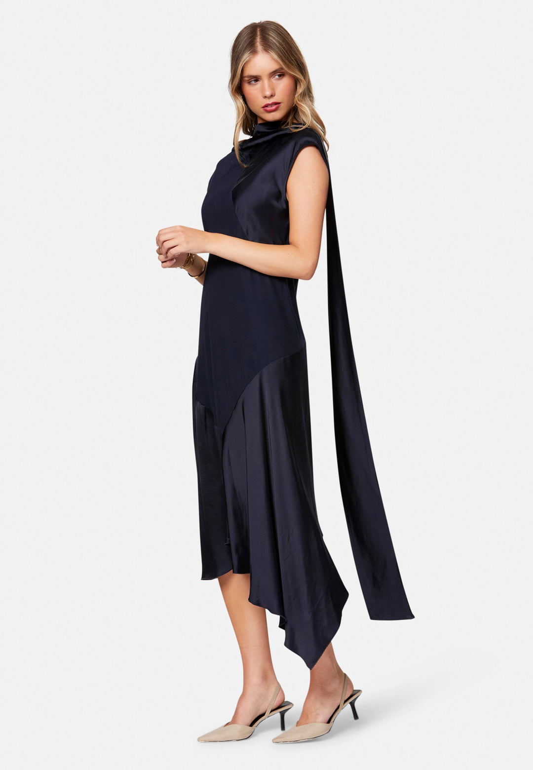Carmin, the modern occasion dress with quiet drama. Cut from fluid, silk-touch satin in deep navy, it skims rather than clings, with a jewel neckline. Bias-cut panels and an asymmetric handkerchief hem add interest, while cap sleeves offer extra coverage. Style it with barely-there heels for evening, or a sharp blazer for city events.