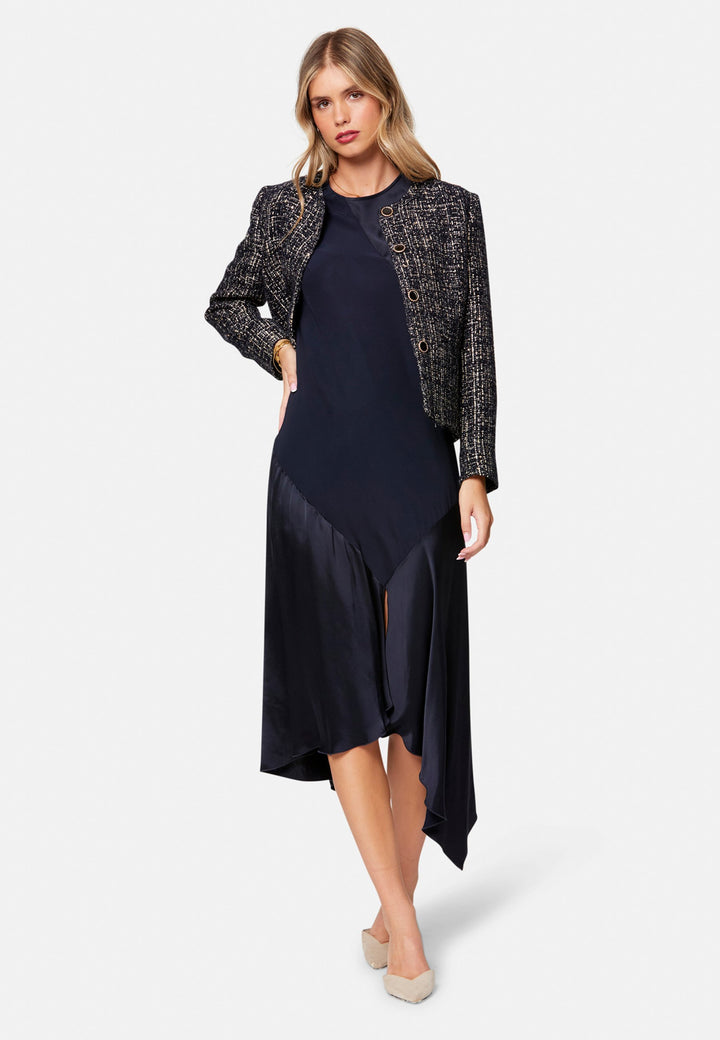 Carmin, the modern occasion dress with quiet drama. Cut from fluid, silk-touch satin in deep navy, it skims rather than clings, with a jewel neckline. Bias-cut panels and an asymmetric handkerchief hem add interest, while cap sleeves offer extra coverage. Style it with barely-there heels for evening, or a sharp blazer for city events.