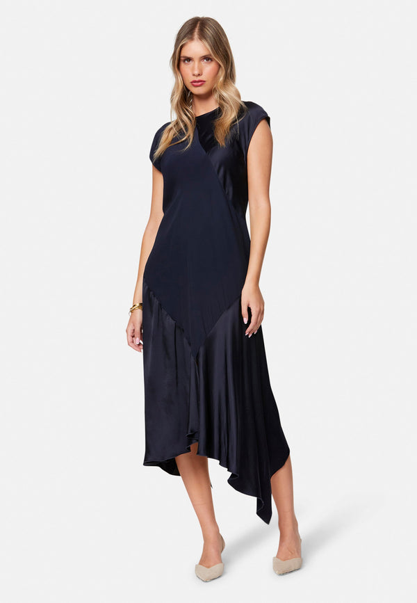 Carmin, the modern occasion dress with quiet drama. Cut from fluid, silk-touch satin in deep navy, it skims rather than clings, with a jewel neckline. Bias-cut panels and an asymmetric handkerchief hem add interest, while cap sleeves offer extra coverage. Style it with barely-there heels for evening, or a sharp blazer for city events.