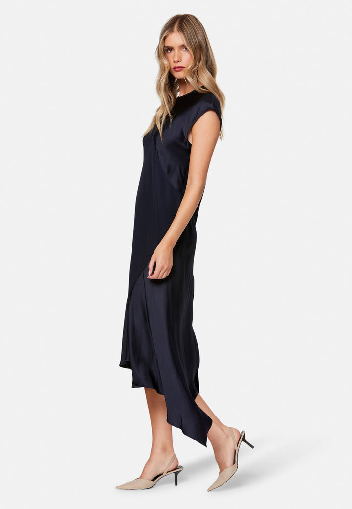 Carmin, the modern occasion dress with quiet drama. Cut from fluid, silk-touch satin in deep navy, it skims rather than clings, with a jewel neckline. Bias-cut panels and an asymmetric handkerchief hem add interest, while cap sleeves offer extra coverage. Style it with barely-there heels for evening, or a sharp blazer for city events.