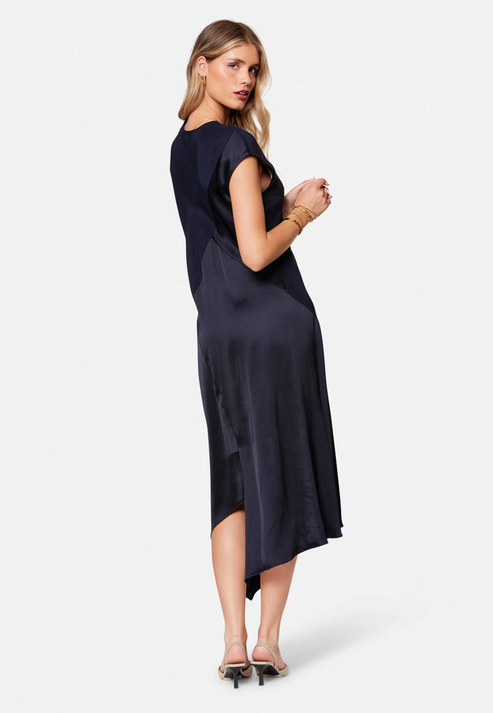 Carmin, the modern occasion dress with quiet drama. Cut from fluid, silk-touch satin in deep navy, it skims rather than clings, with a jewel neckline. Bias-cut panels and an asymmetric handkerchief hem add interest, while cap sleeves offer extra coverage. Style it with barely-there heels for evening, or a sharp blazer for city events.