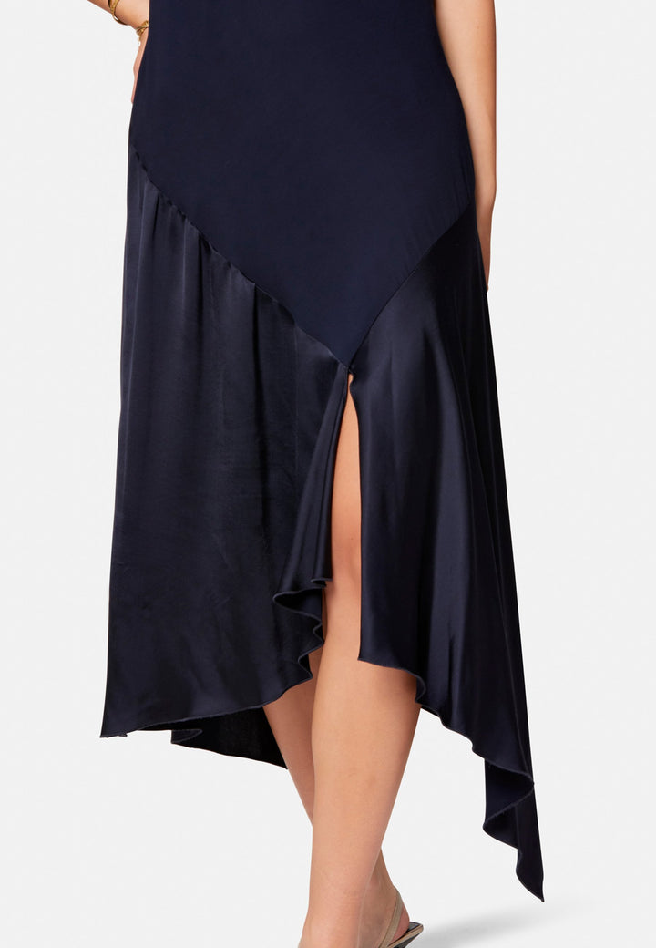 Carmin, the modern occasion dress with quiet drama. Cut from fluid, silk-touch satin in deep navy, it skims rather than clings, with a jewel neckline. Bias-cut panels and an asymmetric handkerchief hem add interest, while cap sleeves offer extra coverage. Style it with barely-there heels for evening, or a sharp blazer for city events.