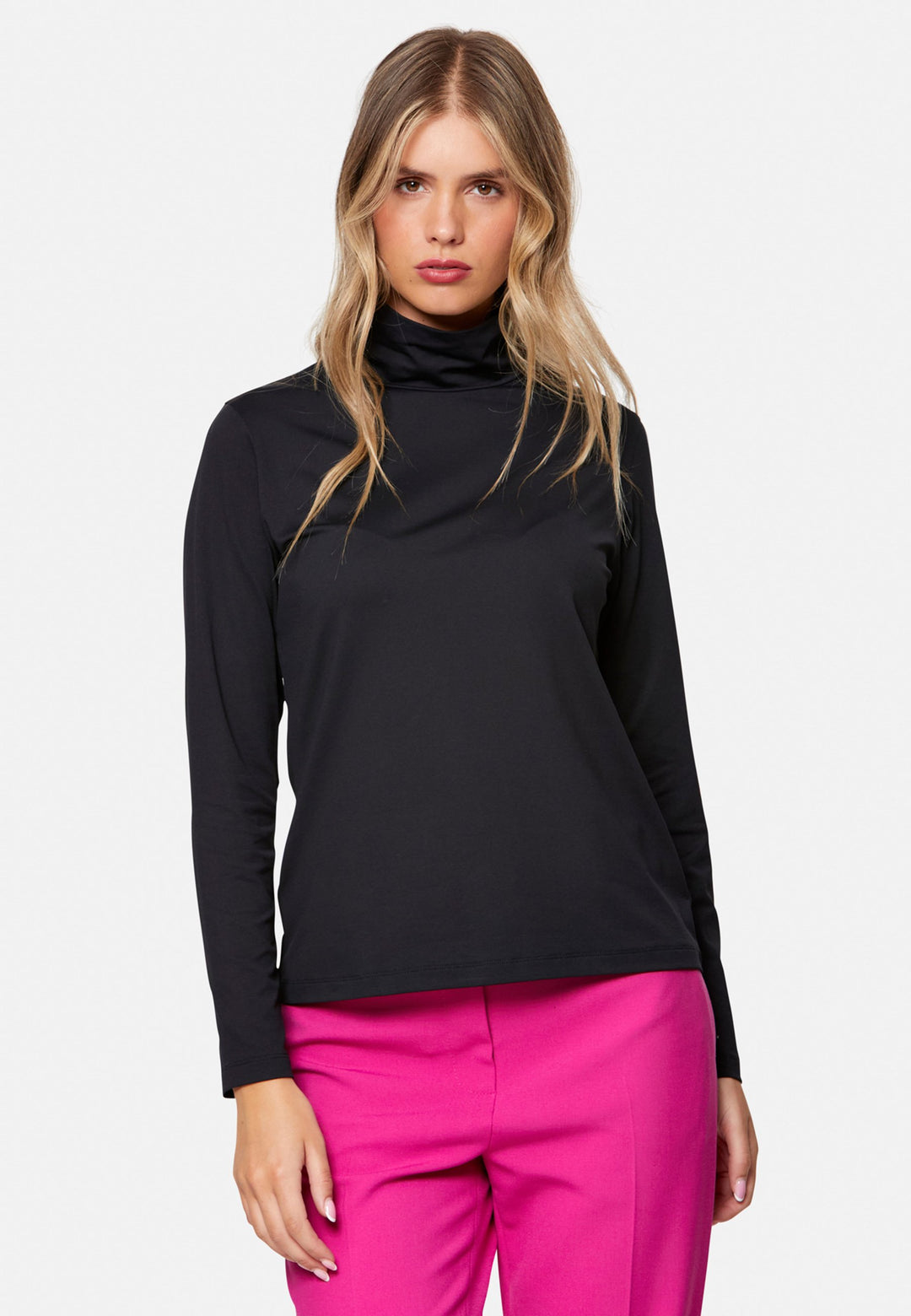 woman wearing high neck and long-sleeved black top with pink trouser