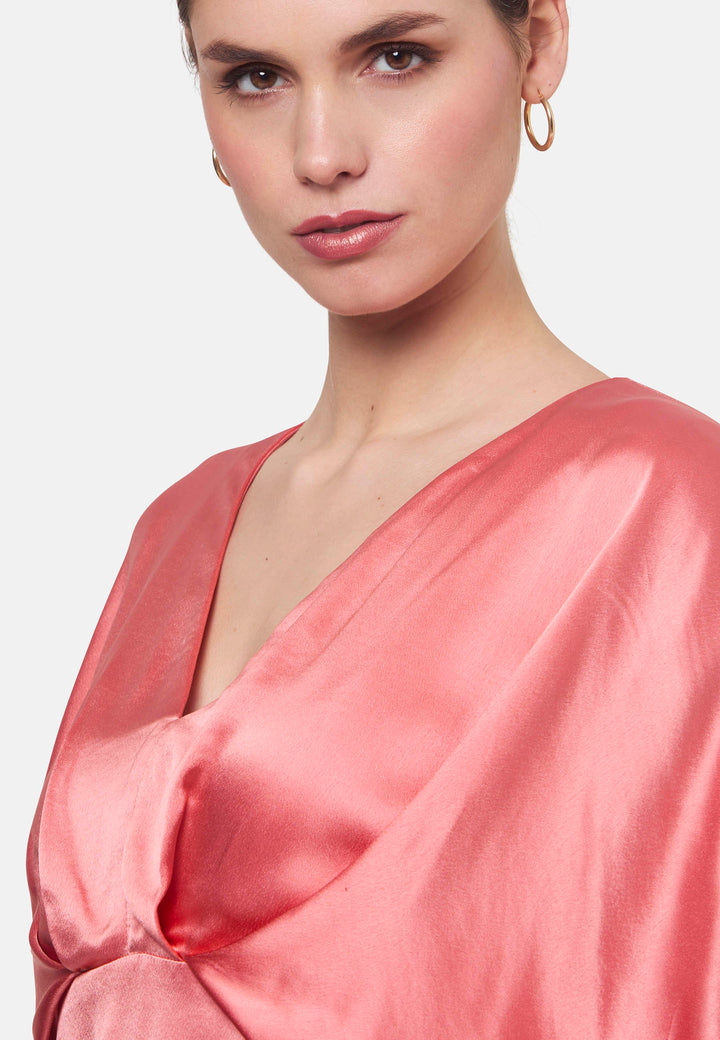 Eabha, the coral rose dress with quiet glamour. Cut from fluid, silk-touch satin, it frames the neckline with a gentle V and draped kimono sleeves, then gathers into under-bust pleats that flatter the waistline. The column midi skirt skims beautifully with discreet side seam pockets and slits for ease, finished with a neat keyhole back. Just add barely-there heels and gold jewellery.