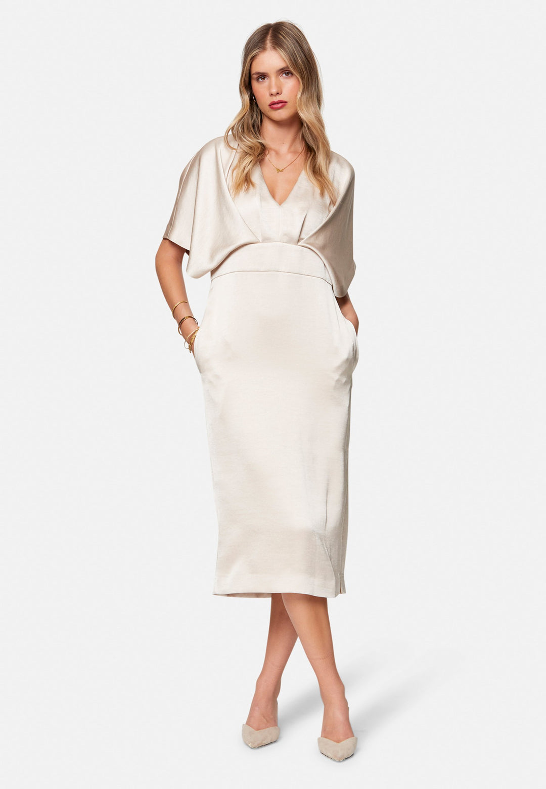 Eabha, the ivory dress with quiet glamour. Cut from fluid, silk-touch satin in a soft oyster hue, it frames the neckline with a gentle V and draped kimono sleeves, then gathers into under-bust pleats that flatter the waistline. The column midi skirt skims beautifully with discreet side seam pockets and slits for ease, finished with a neat keyhole back. Just add barely-there heels and gold jewellery.