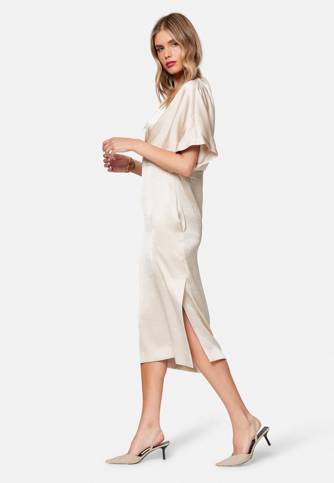 Eabha, the ivory dress with quiet glamour. Cut from fluid, silk-touch satin in a soft oyster hue, it frames the neckline with a gentle V and draped kimono sleeves, then gathers into under-bust pleats that flatter the waistline. The column midi skirt skims beautifully with discreet side seam pockets and slits for ease, finished with a neat keyhole back. Just add barely-there heels and gold jewellery.