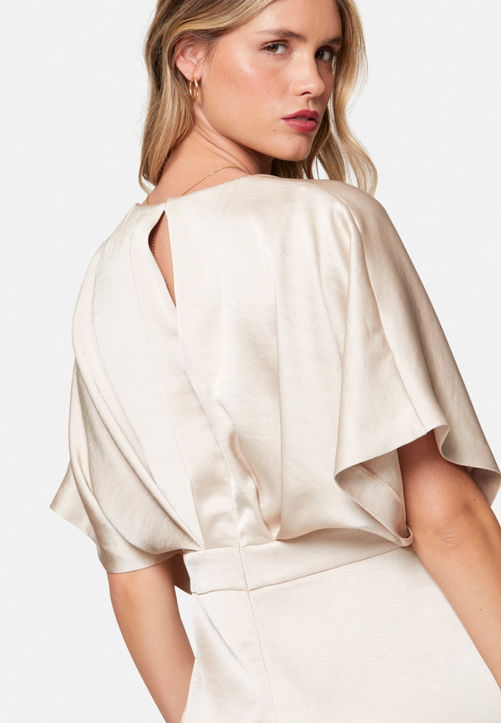 Eabha, the ivory dress with quiet glamour. Cut from fluid, silk-touch satin in a soft oyster hue, it frames the neckline with a gentle V and draped kimono sleeves, then gathers into under-bust pleats that flatter the waistline. The column midi skirt skims beautifully with discreet side seam pockets and slits for ease, finished with a neat keyhole back. Just add barely-there heels and gold jewellery.
