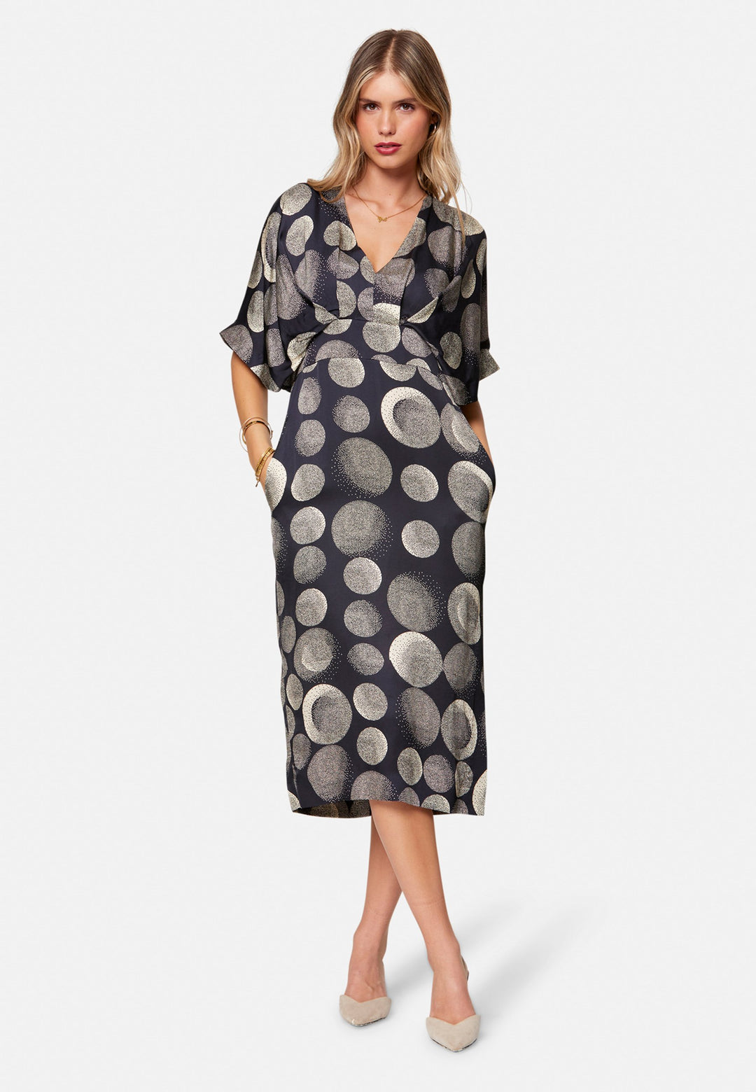 Eabha, the print dress with quiet drama. In fluid, silk-touch navy satin scattered with ivory lunar dots, it features a soft V-neckline, kimono sleeves and under-bust pleats that flatter the waistline. The column midi skirt is finished with discreet side seam pockets and a slit for ease, plus a neat keyhole back. Just add heels and minimal jewellery.