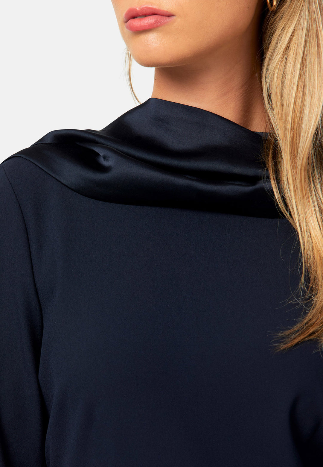 Kristy, a modern take on the dropped waist. Cut from plain-weave worsted navy fabric with a touch of stretch, the dress contrasts with a fluid viscose satin skirt that flows softly from the low hip. Designed with a clean round neckline, long fitted sleeves, a dropped waistline and a gently flared midi skirt that falls to mid-calf. The tonal fabric pairing creates subtle dimension, while the detachable satin scarf/belt can be cinched at the waist or draped elegantly around the neck. 