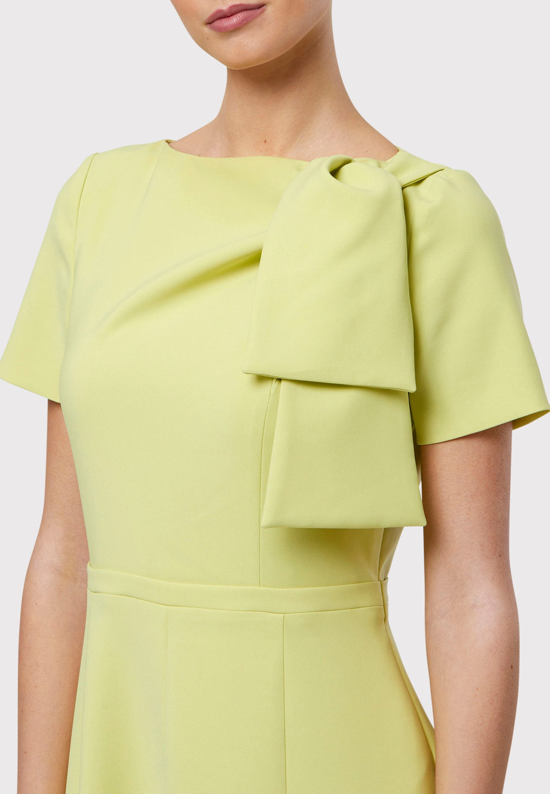 Introducing the Laoise Lime Dress, a refined statement piece designed exclusively for special occasions. Adorned with T-shirt-length sleeves and a meticulously fitted bodice, this dress features an elegant tie detail on the shoulder, creating a sophisticated pleat across the bust. The highlight of this ensemble is its fit-and-flare panelled skirt, gracefully cascading into a flattering A-line shape that exudes timeless elegance and movement.