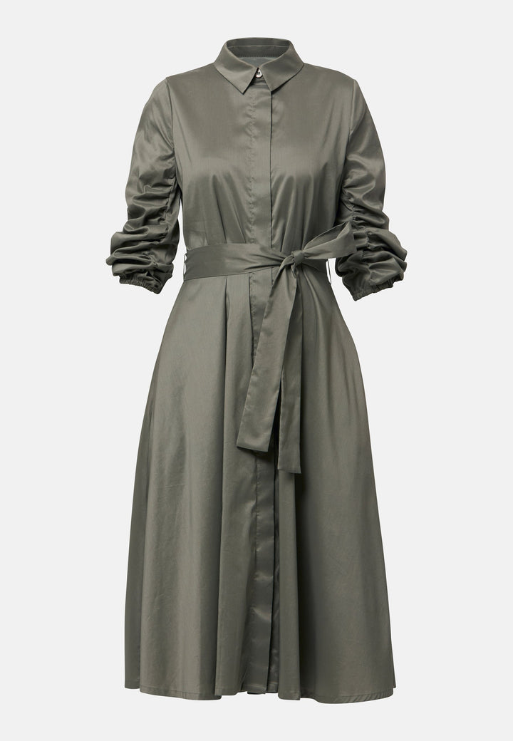 The Leah Olive midi shirt dress combines classic tailoring with a feminine touch. Featuring a button-down front and ruched three-quarter length sleeves, it offers versatility and style. The detachable tie belt cinches the waist, while the gently flared skirt provides a flattering silhouette with essential side seam pockets.