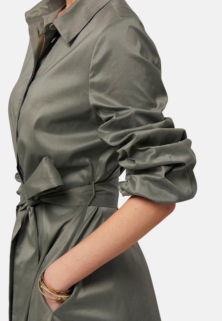 The Leah Olive midi shirt dress combines classic tailoring with a feminine touch. Featuring a button-down front and ruched three-quarter length sleeves, it offers versatility and style. The detachable tie belt cinches the waist, while the gently flared skirt provides a flattering silhouette with essential side seam pockets.