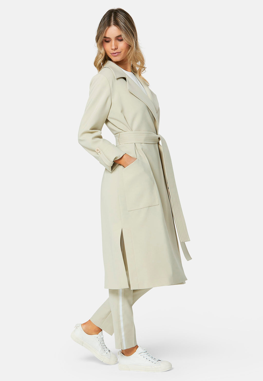 Lydiah captures the essence of sophisticated simplicity with its elegant design. This fluid trench coat features a neutral bone hue that radiates timeless appeal. It comes with a meticulously row-stitched, detachable belt that adds a touch of refinement, allowing you the flexibility to cinch it at the waist or wear it open for a relaxed look.