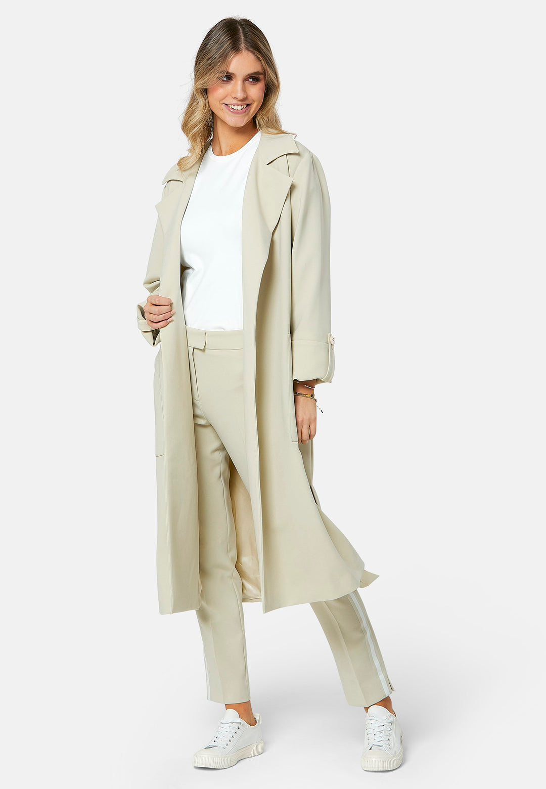 Lydiah captures the essence of sophisticated simplicity with its elegant design. This fluid trench coat features a neutral bone hue that radiates timeless appeal. It comes with a meticulously row-stitched, detachable belt that adds a touch of refinement, allowing you the flexibility to cinch it at the waist or wear it open for a relaxed look.