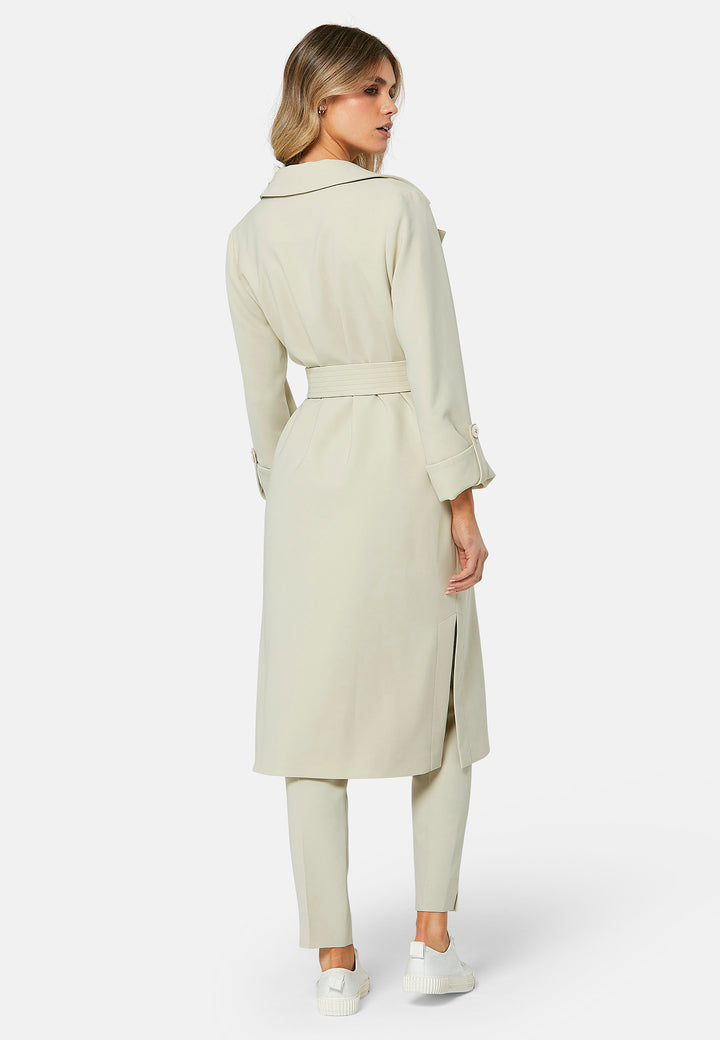 Lydiah captures the essence of sophisticated simplicity with its elegant design. This fluid trench coat features a neutral bone hue that radiates timeless appeal. It comes with a meticulously row-stitched, detachable belt that adds a touch of refinement, allowing you the flexibility to cinch it at the waist or wear it open for a relaxed look.