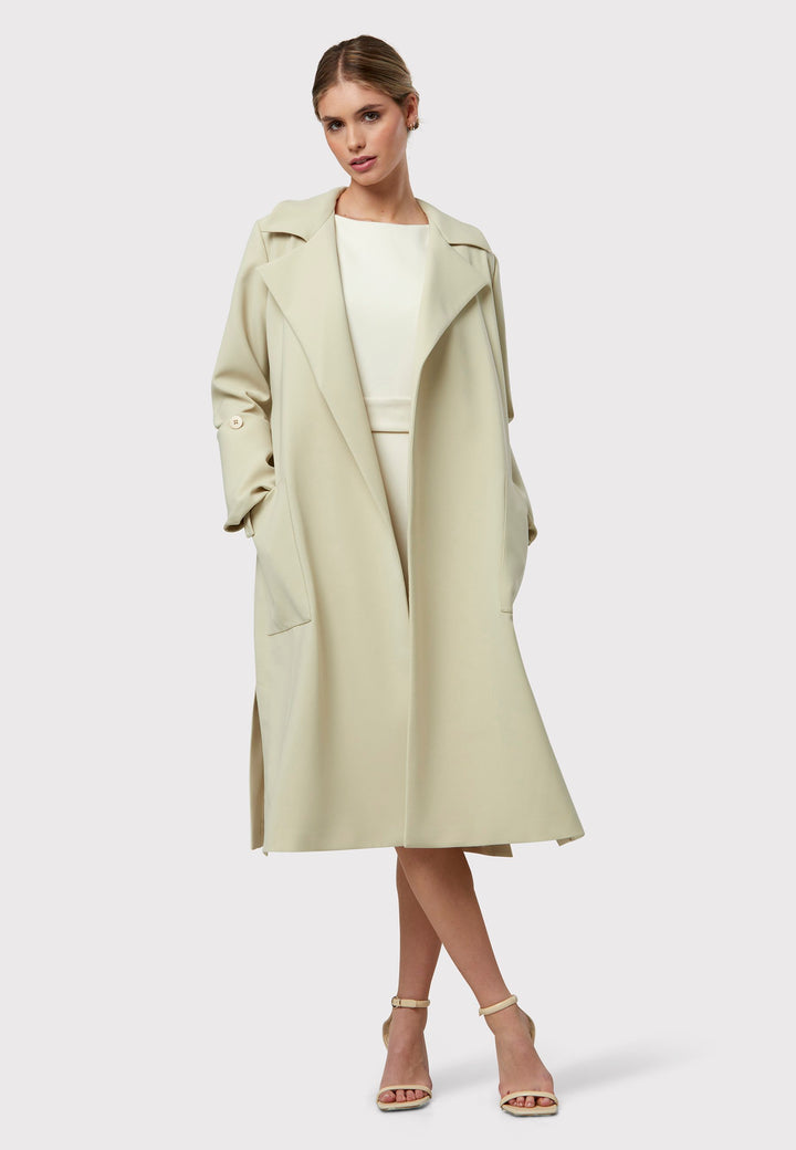 Lydiah captures the essence of sophisticated simplicity with its elegant design. This fluid trench coat features a neutral bone hue that radiates timeless appeal. It comes with a meticulously row-stitched, detachable belt that adds a touch of refinement, allowing you the flexibility to cinch it at the waist or wear it open for a relaxed look.