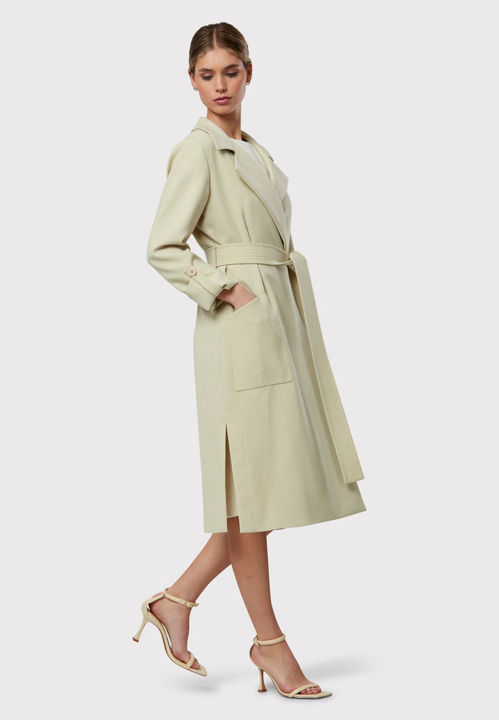 Lydiah captures the essence of sophisticated simplicity with its elegant design. This fluid trench coat features a neutral bone hue that radiates timeless appeal. It comes with a meticulously row-stitched, detachable belt that adds a touch of refinement, allowing you the flexibility to cinch it at the waist or wear it open for a relaxed look.