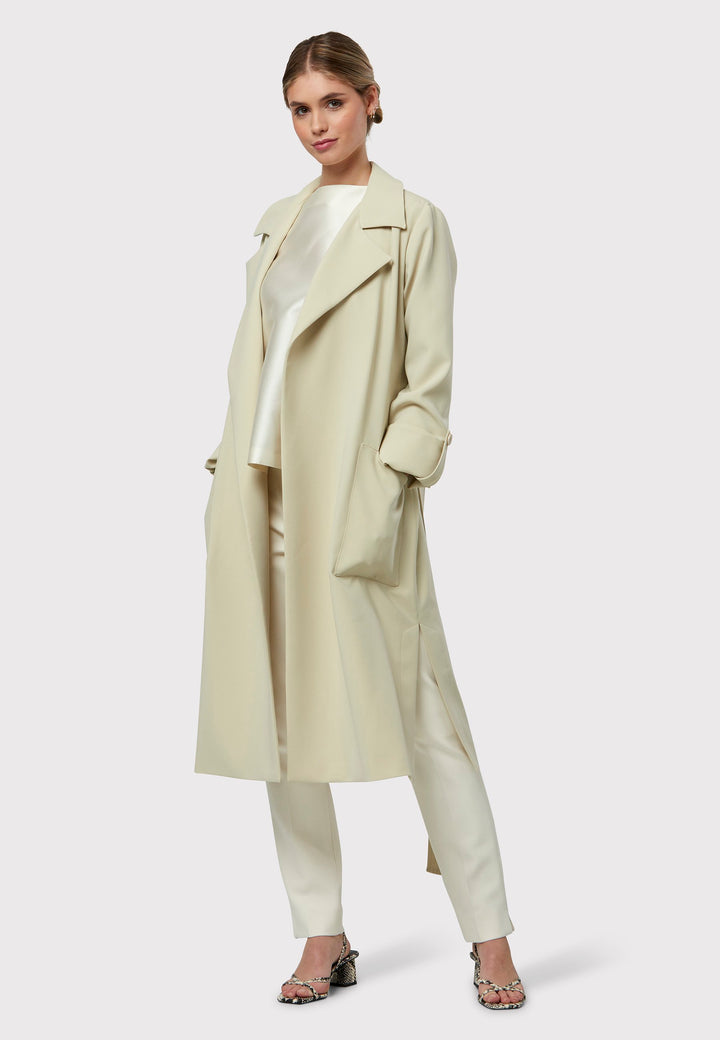 Lydiah captures the essence of sophisticated simplicity with its elegant design. This fluid trench coat features a neutral bone hue that radiates timeless appeal. It comes with a meticulously row-stitched, detachable belt that adds a touch of refinement, allowing you the flexibility to cinch it at the waist or wear it open for a relaxed look.